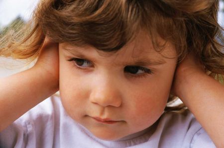 bambino in primo piano con le mani sulle orecchie